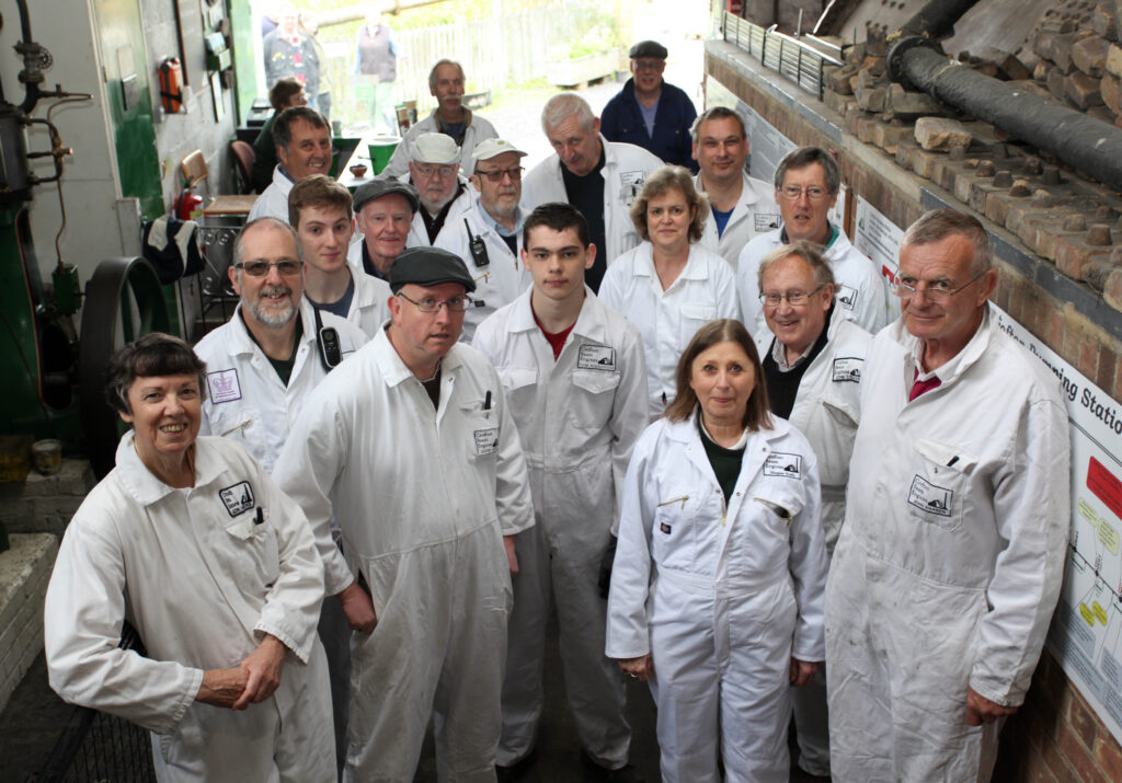 Crofton volunteers (adults) in white boiler suits standing in a group in Crofton's Boiler House